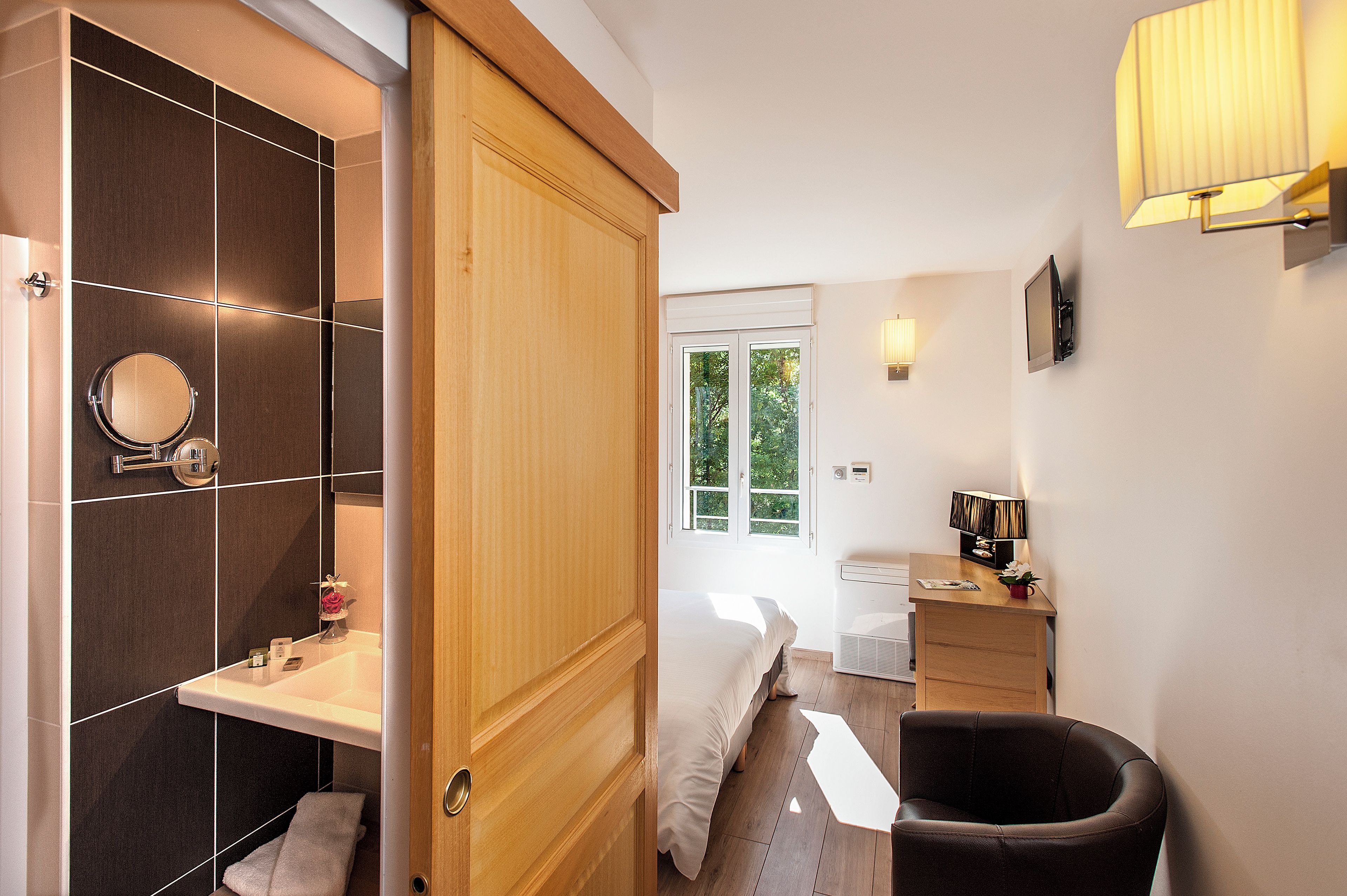 A modern bathroom with a wooden vanity, a round mirror, and a toilet.