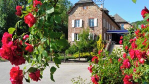 Un edificio de piedra con un cartel que dice 'HOTEL', rodeado de exuberante vegetación y rosas rojas.