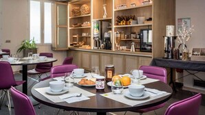 Un comedor con mesas redondas, sillas moradas y un bufé de desayuno con diversos alimentos y bebidas.
