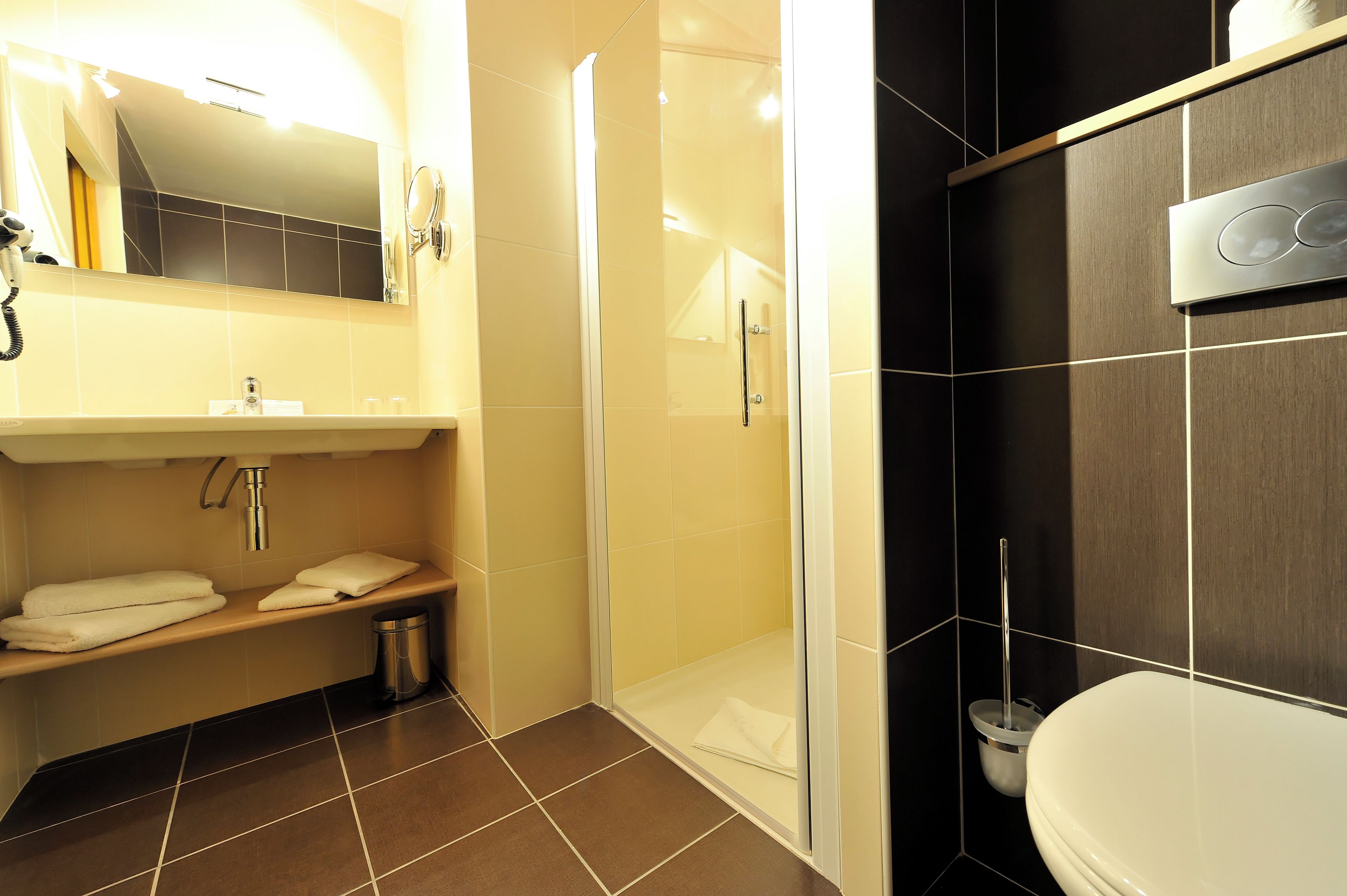 A bathroom with a shower, toilet, sink, and towel rack.