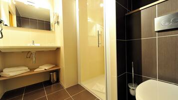 A bathroom with a shower, toilet, sink, and towel rack.
