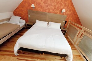 Una habitación con dos camas, suelo de madera y techo inclinado.