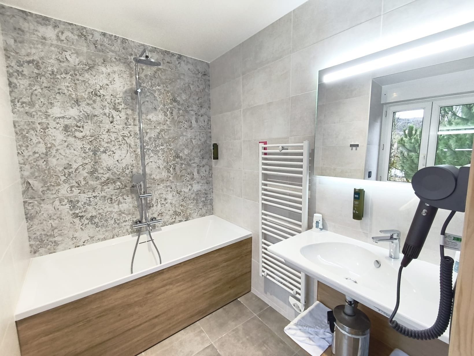 Een moderne badkamer met een douche, wastafel en haardroger.