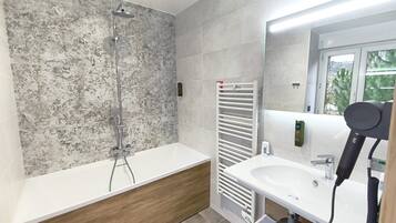 Een moderne badkamer met een douche, wastafel en haardroger.