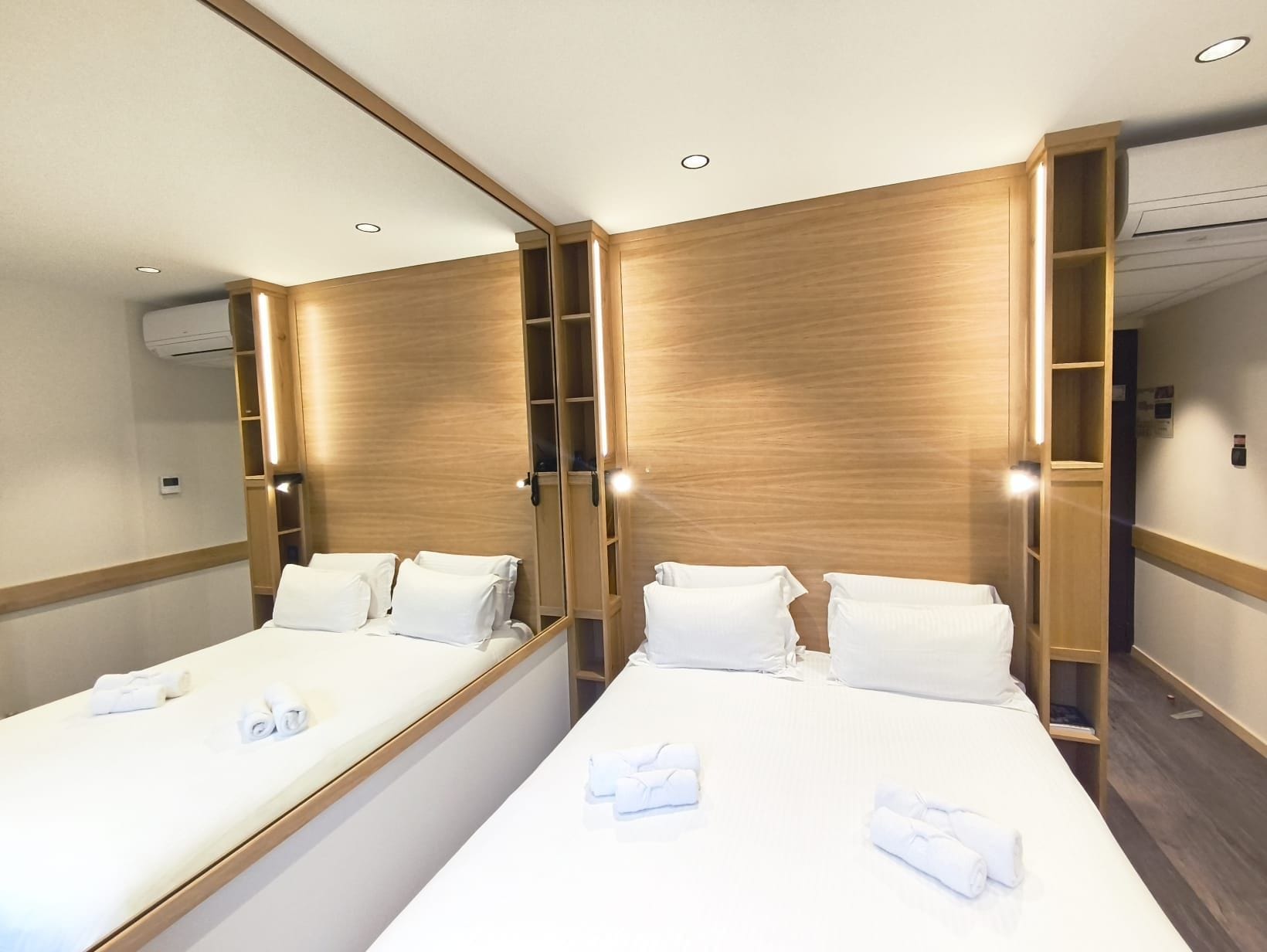 Une chambre d’hôtel avec deux lits, des lambris en bois et des étagères intégrées.