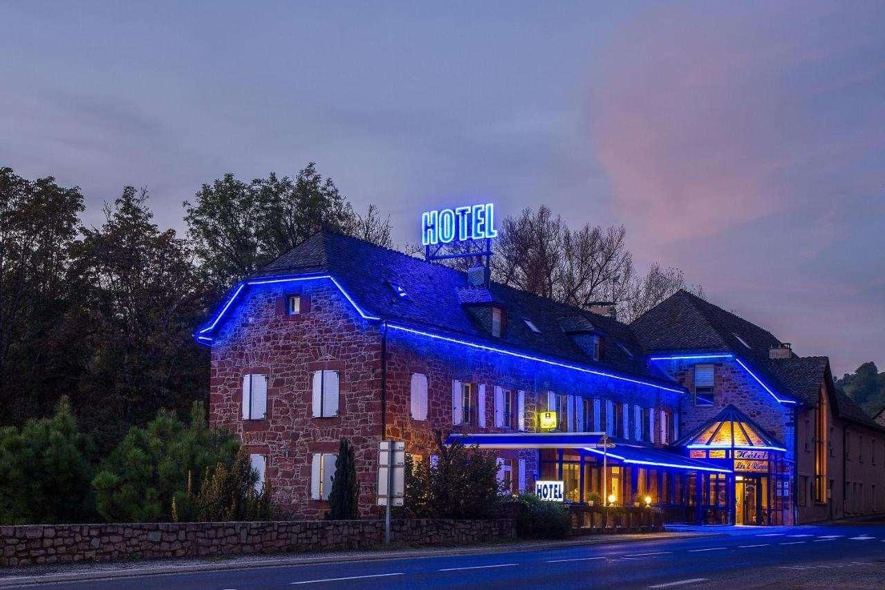 Un hotel con fachada de piedra, un letrero de neón y un estilo arquitectónico clásico.
