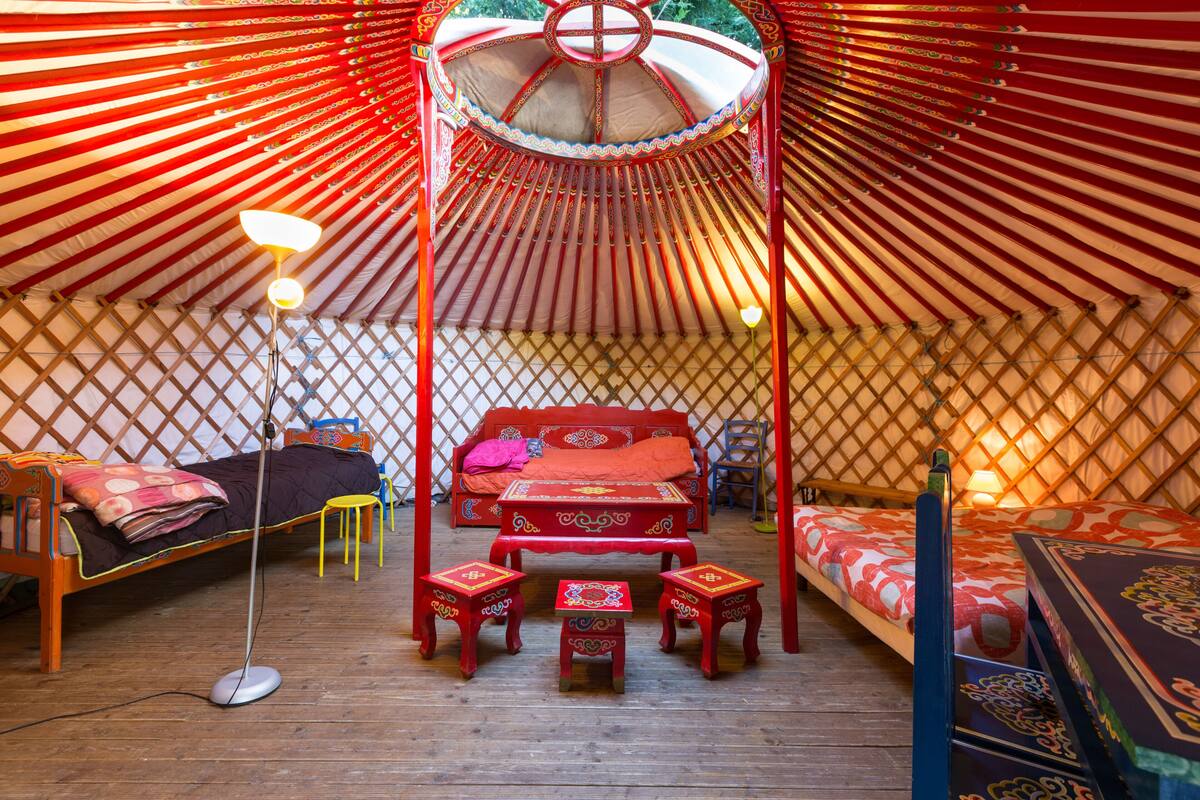Eine traditionelle Jurte mit einem Bett, einem kleinen Tisch und einem Stuhl.