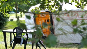 Una tenda con una porta, un tavolo e una sedia in un prato.