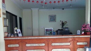 A reception desk with marble inlays, a framed certificate, and a potted plant. - Hotel Lautze Indah (Jakarta)