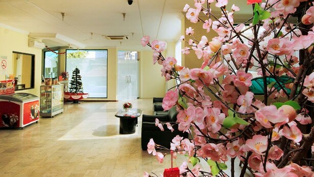 A spacious lobby with a Christmas tree, a reception desk, and a large artificial cherry blossom tree. - Hotel Lautze Indah (Jakarta)