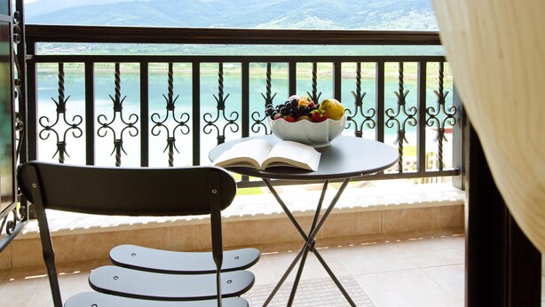 A balcony with a table, a chair, and a bowl of fruit and an open book. - Hyatt Regency Pravets Resort (Pravets)