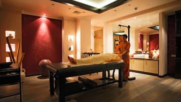 Relax in a serene spa room with a massage table, mirror, reception desk, and seating area.