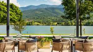 An outdoor dining area with wicker chairs and tables, overlooking a lake and mountains. - Hyatt Regency Pravets Resort (Pravets)