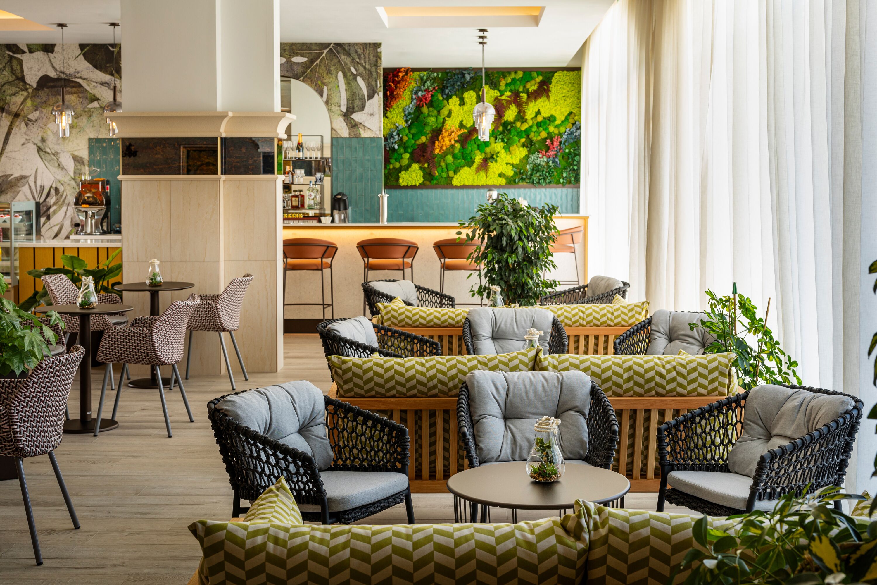 Un área de descanso moderna con mobiliario de mimbre, un bar y una pared verde vibrante.