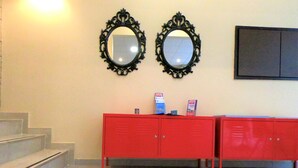 A reception area with two ornate mirrors, a red counter, and a staircase. - Hotel Achillion (Piraeus)
