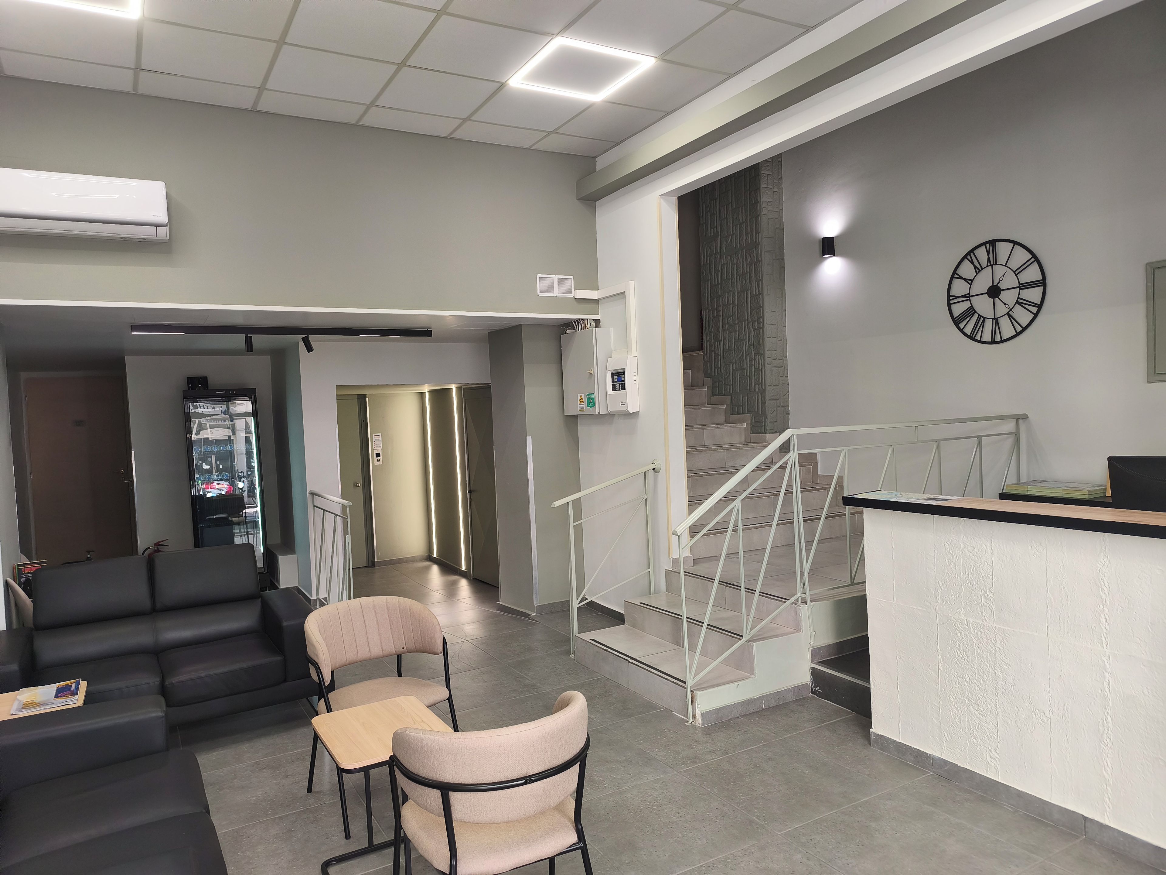 Ein modernes Interieur mit einer Rezeption, einer Sitzecke und einer Treppe.