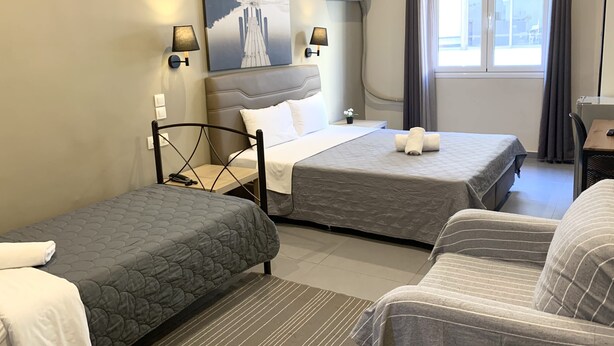 A hotel room with two beds, a desk, a chair, a painting on the wall, and a window with curtains. - Hotel Achillion (Piraeus)