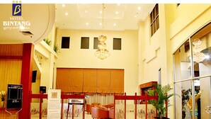 Um hall de hotel com balcão de recepção, área de estar e um lustre grande.