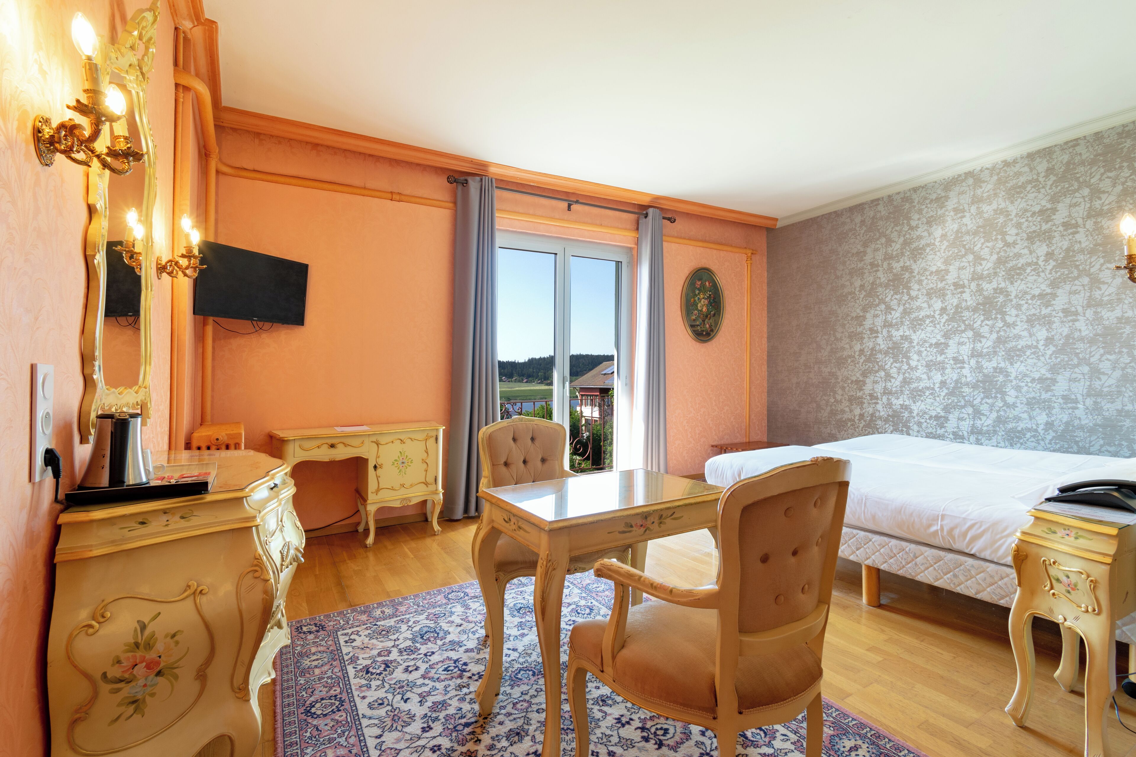 Une chambre d’hôtel équipée d’un lit, d’un bureau, d’une chaise, d’une télévision et offrant une vue sur l’extérieur.