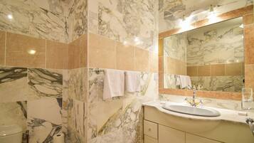 A bathroom with marble walls and a sink with a mirror above it.