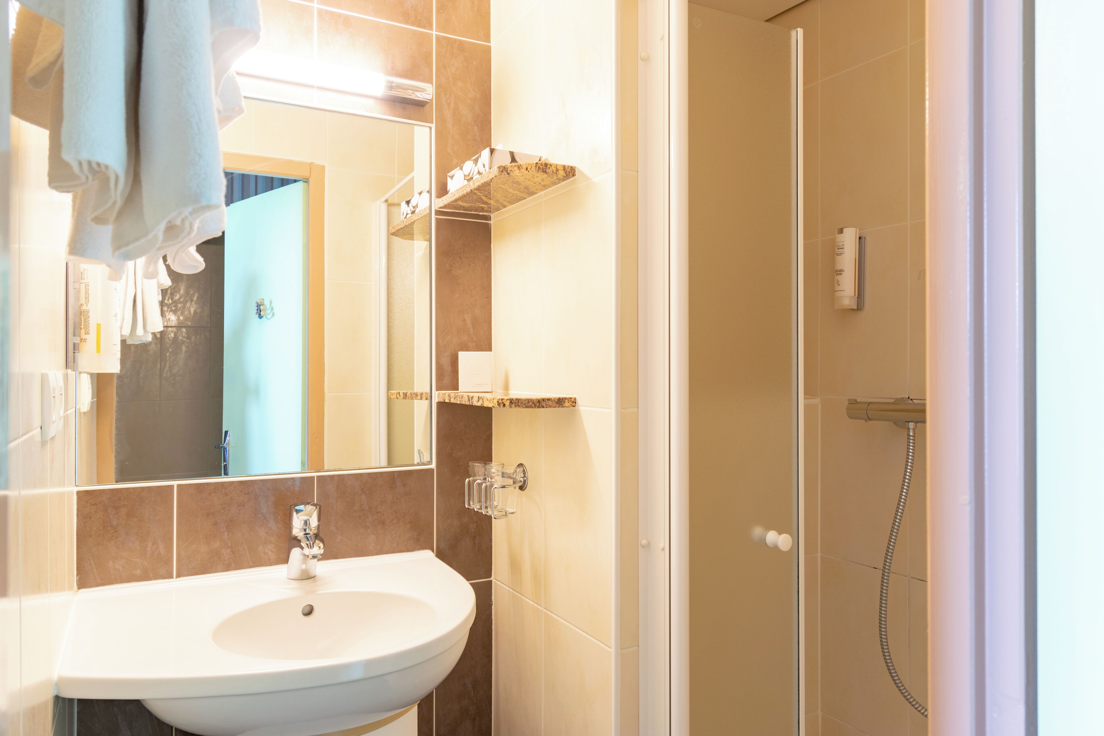 Un baño con lavamanos, espejo, toallero y ducha.