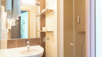 Un baño con lavamanos, espejo, toallero y ducha.
