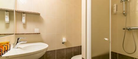 A bathroom with a sink, mirror, and shower.