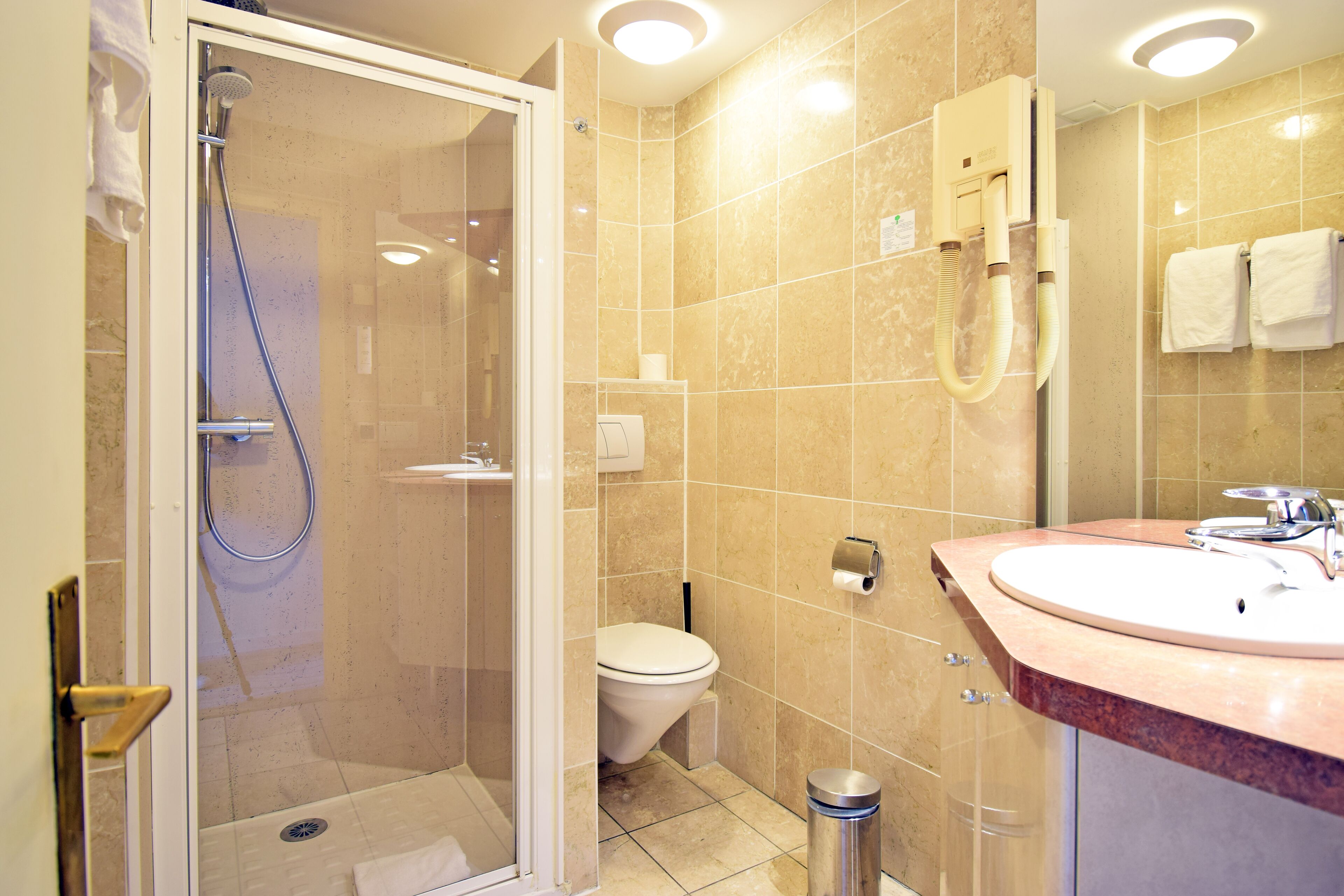 A modern bathroom with a glass-enclosed shower, a white toilet, and a sink with a marble countertop.