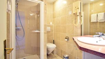 A modern bathroom with a glass-enclosed shower, a white toilet, and a sink with a marble countertop.