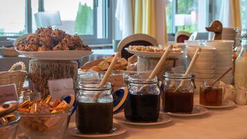 Une table de buffet proposant divers plats, notamment un saladier de biscuits, des pots de sauces et des assiettes de pâtisseries.