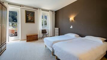 A bedroom with two beds, a wooden bench, a chair, a radiator, and a painting.