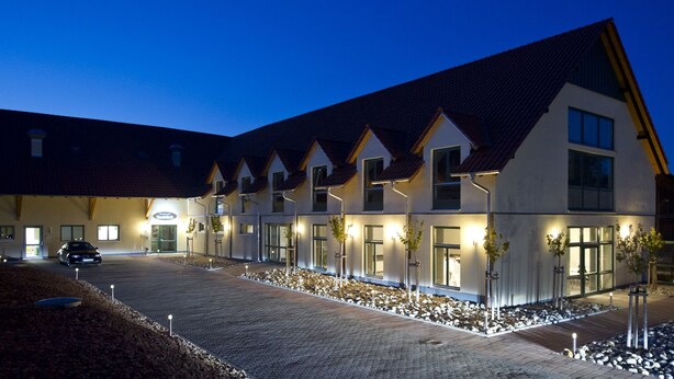 A modern hotel with a symmetrical facade, multiple windows, and a paved driveway.