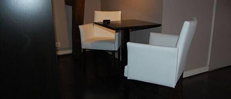A small dining area with a dark wooden table and two white chairs.