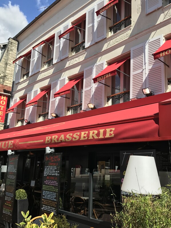 A hotel with red awnings and a sign that reads "HOTEL BRASSERIE."