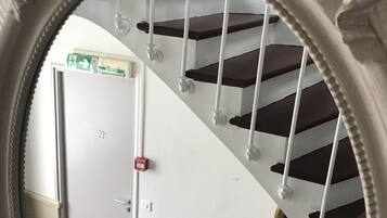 Un espejo circular que refleja una escalera con barandillas blancas y escalones oscuros.