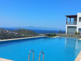 Piscina com vista para o mar e montanhas.