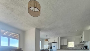 Amplia sala de estar con un sofá grande, una mesa de centro y una cocina al fondo.