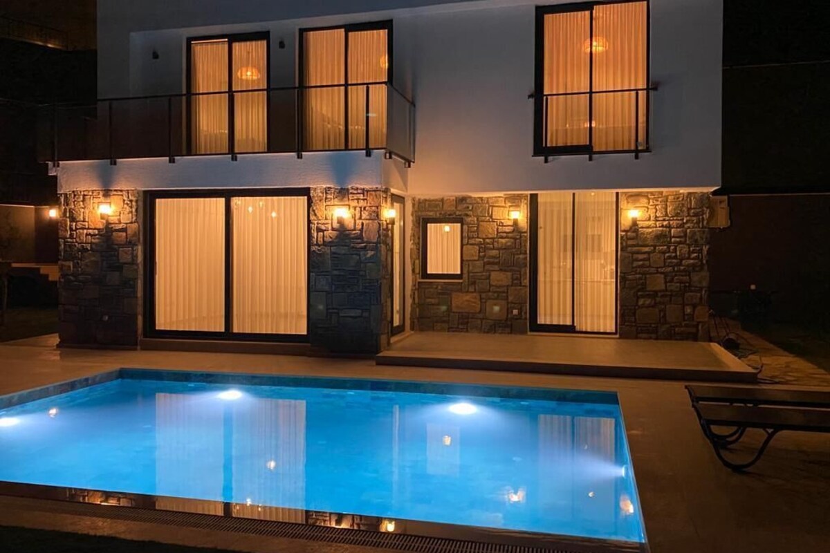 Une maison moderne à deux étages avec une piscine à l’avant.