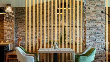 A dining area with a wooden table, two chairs, and a decorative wall with vertical slats.
