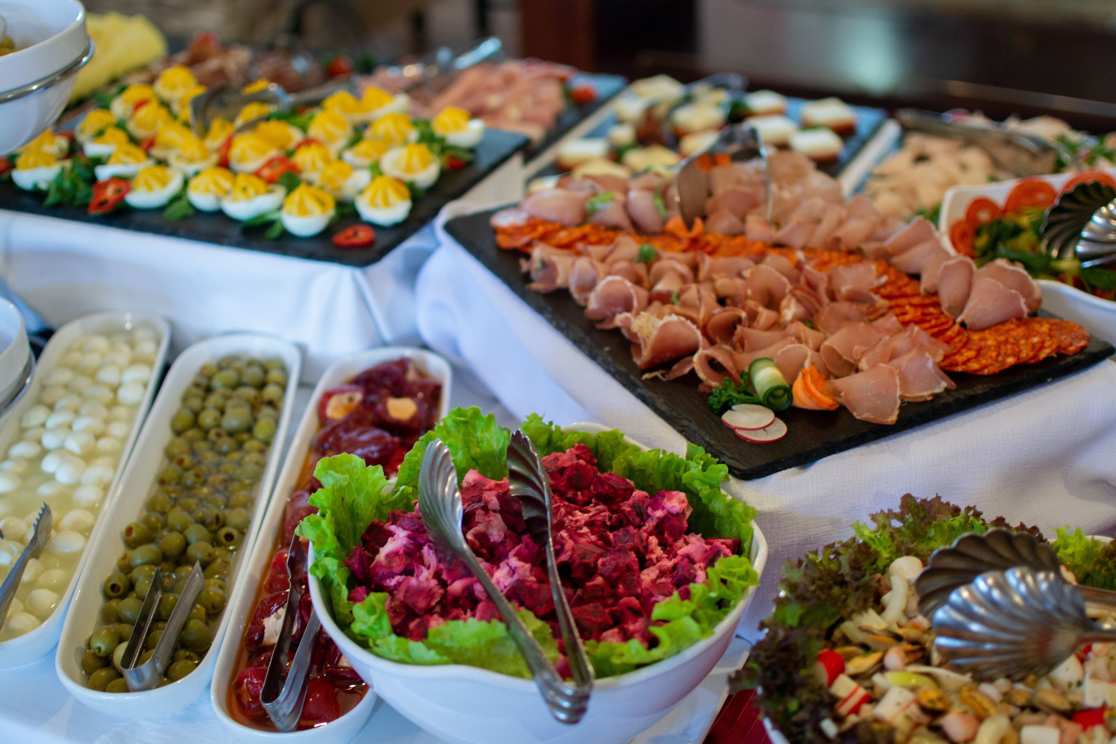 Un buffet proposant une variété de plats, notamment des salades, de la viande et des œufs.