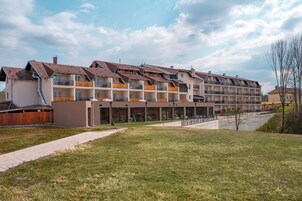Un hotel de varios pisos con balcones, un área exterior cubierta y un patio césped.