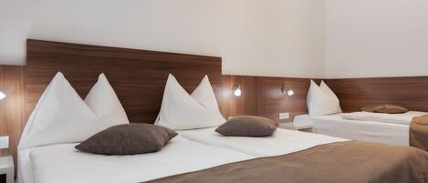 Habitación de hotel con dos camas, cada una con ropa blanca y mantas marrones.