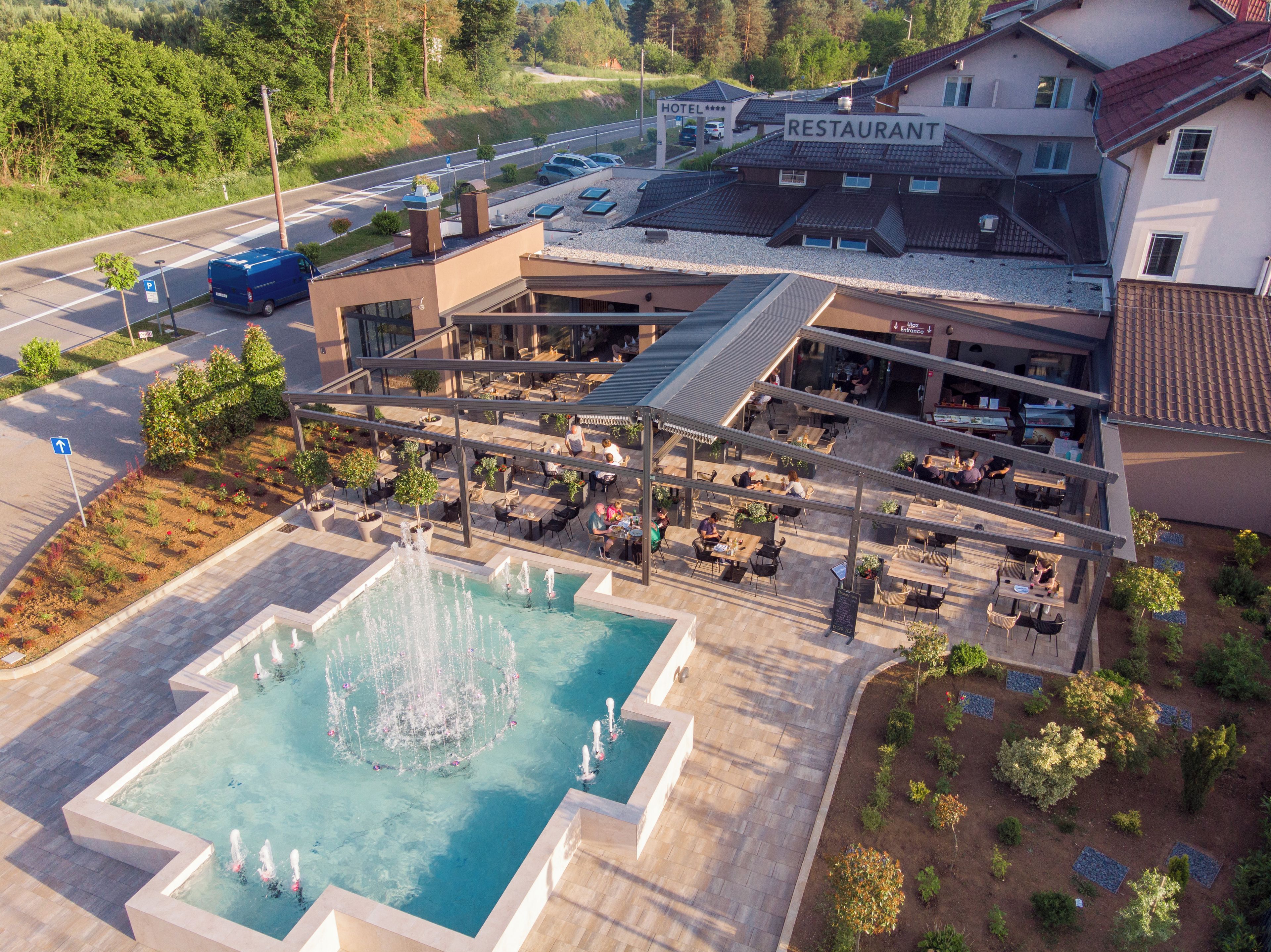 A hotel with a restaurant, outdoor seating, and a swimming pool with a fountain.