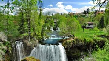 Une cascade entourée d’une végétation luxuriante, sous un ciel dégagé.