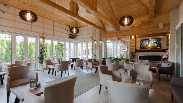 A spacious indoor area with multiple seating arrangements, large windows, and a fireplace. - Hotel Mirjana & Rastoke (Slunj)