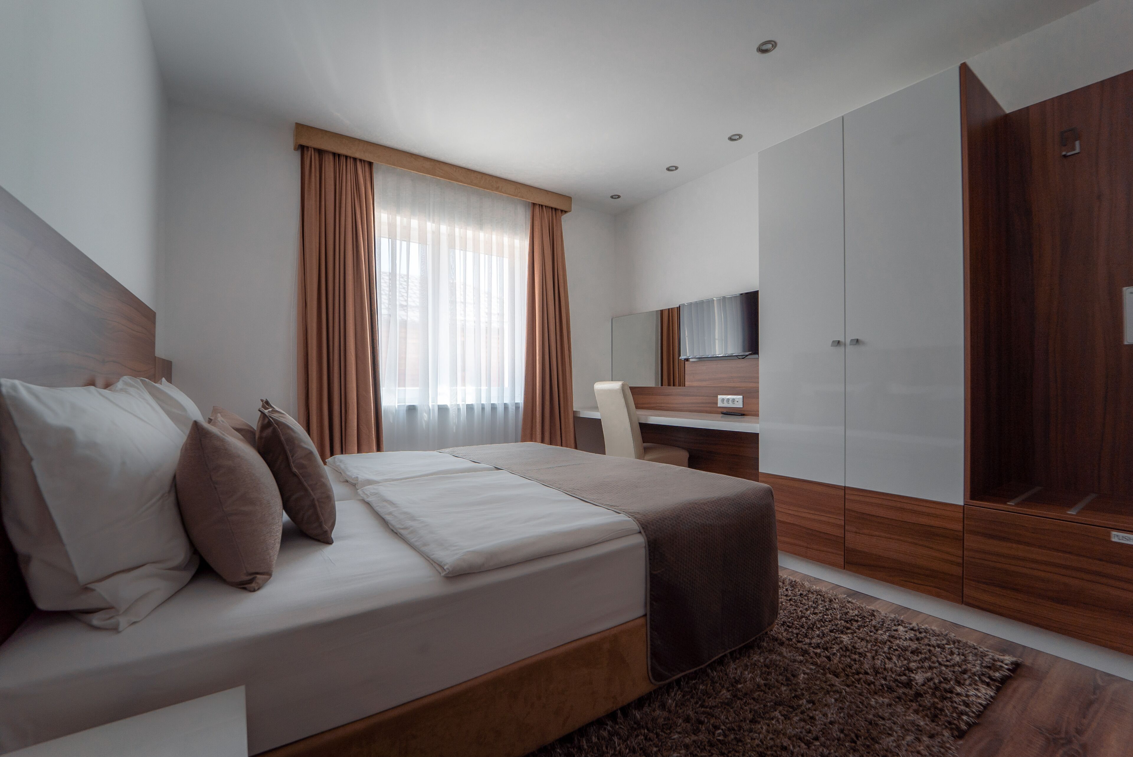 Un dormitorio moderno con cama, escritorio y armario.