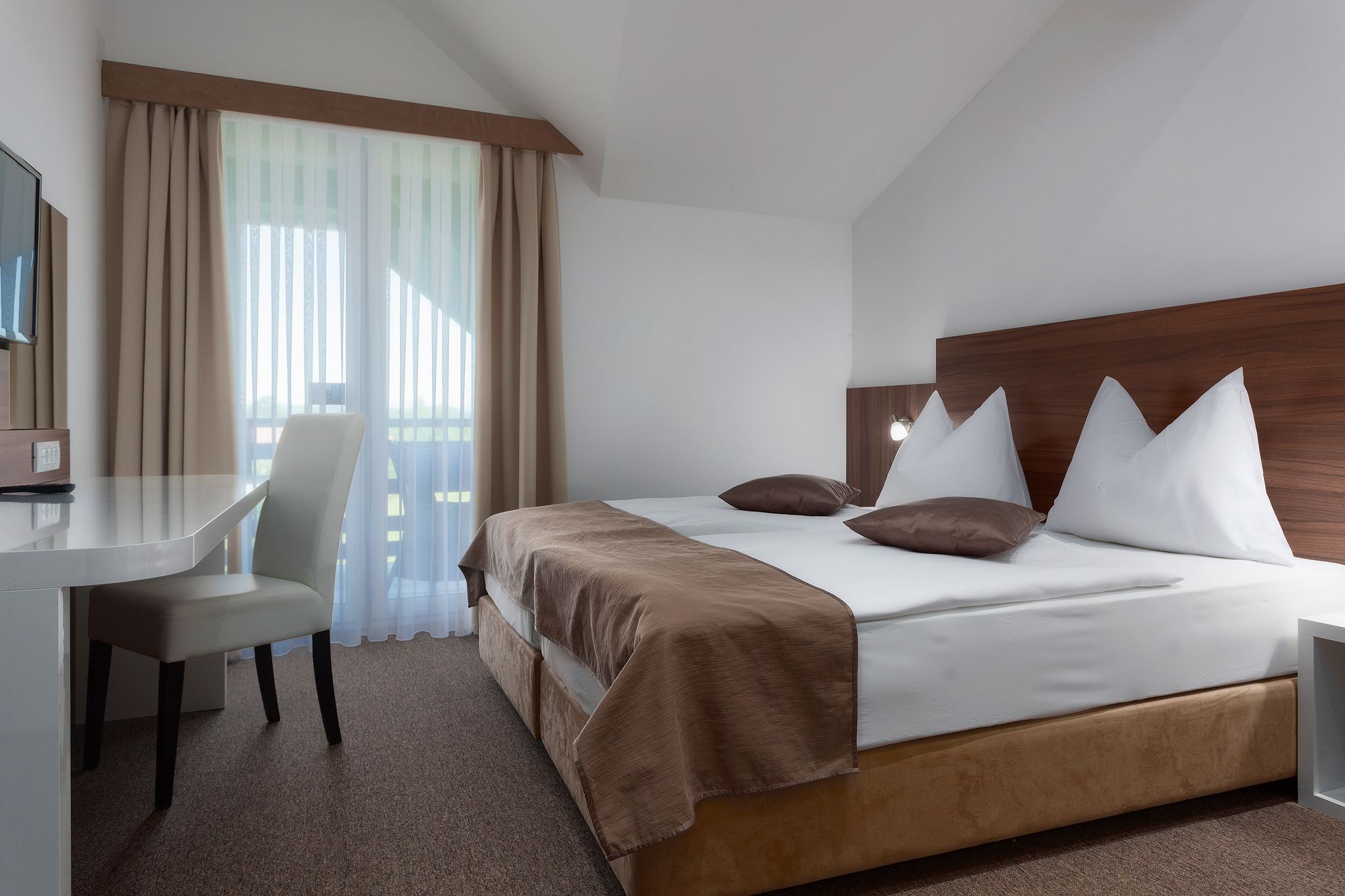 A hotel room with a bed, a desk, and a chair.