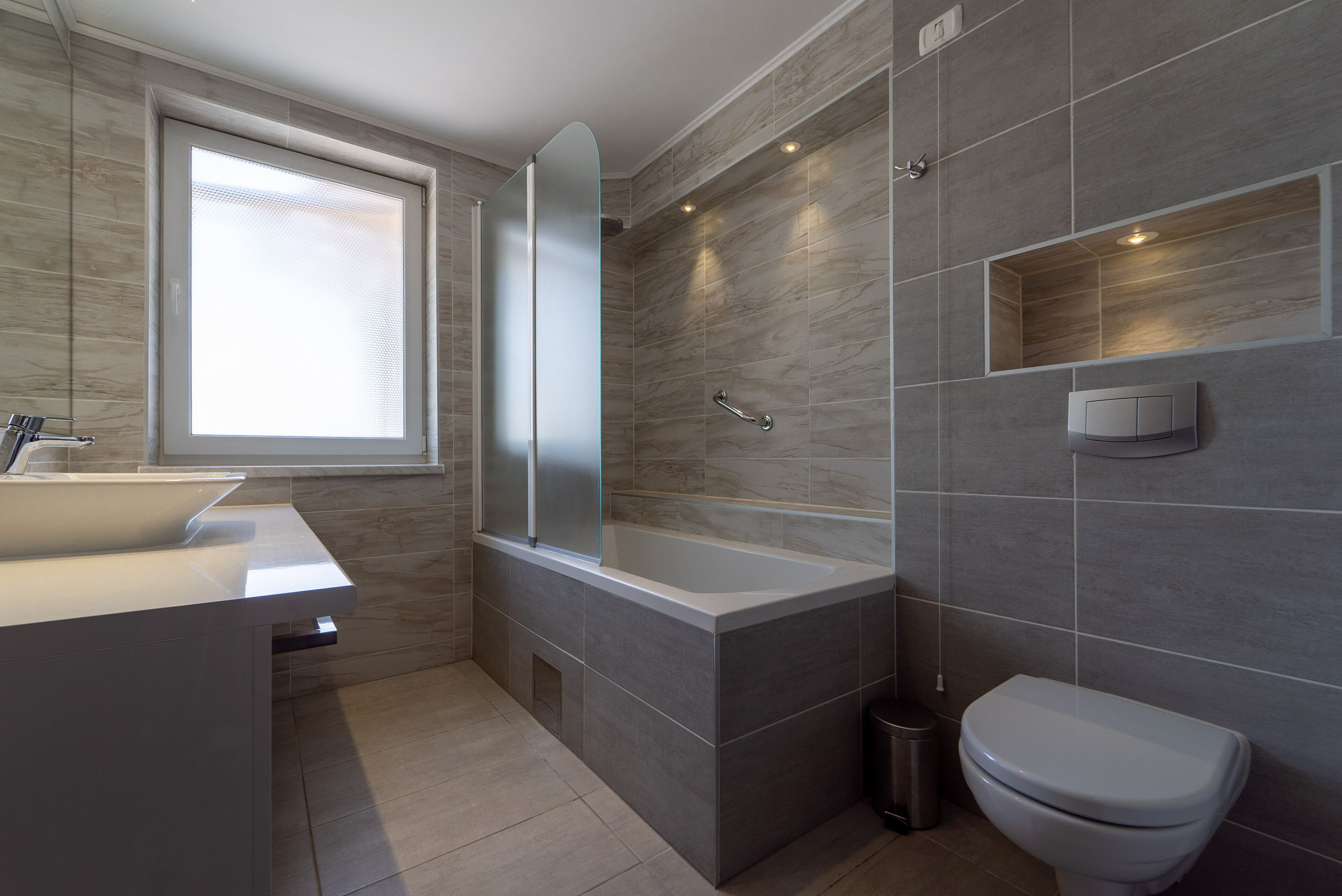 A modern bathroom with a bathtub, toilet, and sink.
