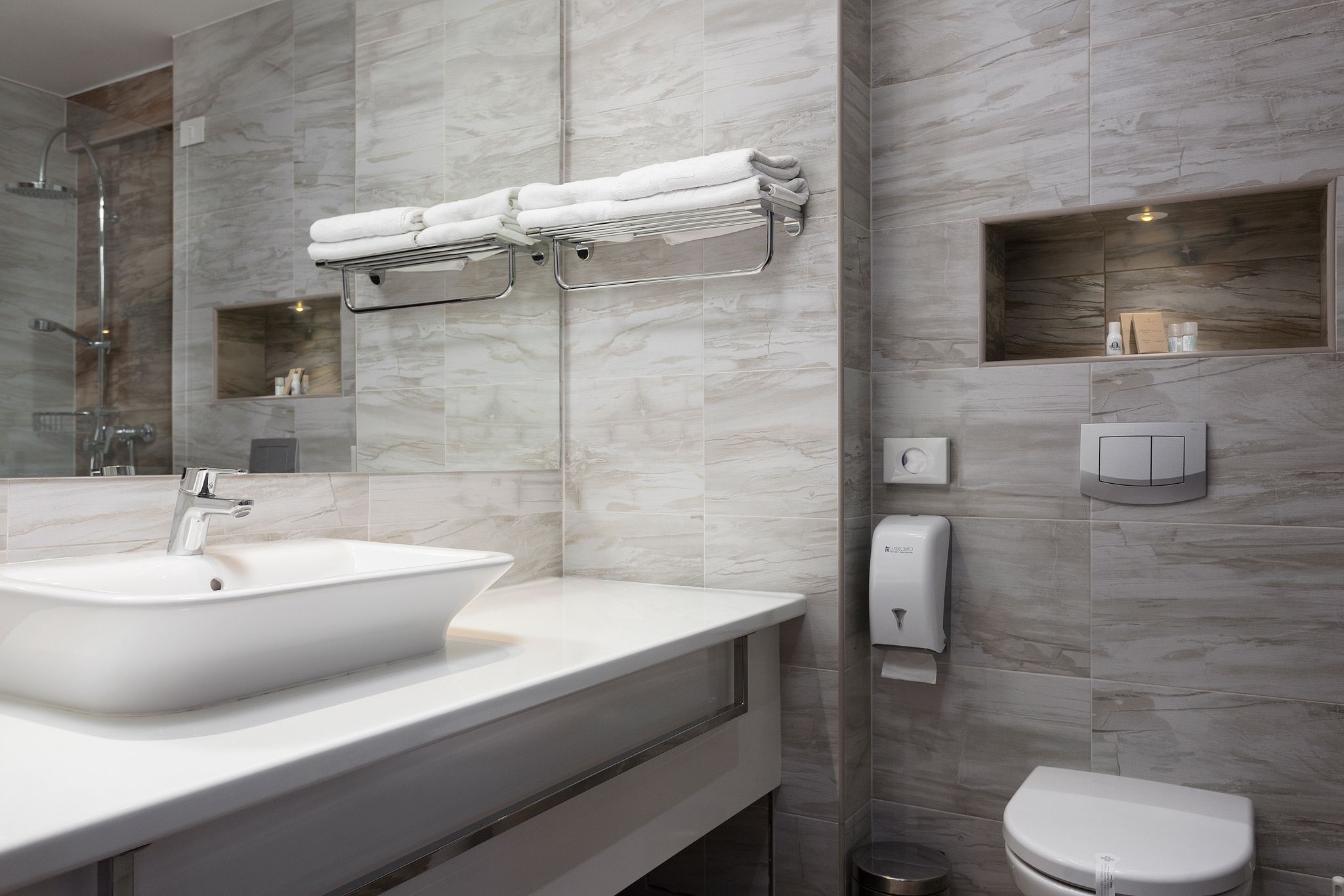 Un baño moderno con un lavamanos grande, un espejo, toallero, inodoro y ducha.