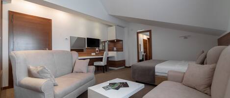 A modern, well-lit room with a sofa, a coffee table, a desk, and a bed.